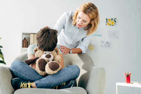 Juegos y herramientas para la atención psicoterapéutica del miedo y ansiedad en niños, niño abrazando un peluche en un sillón