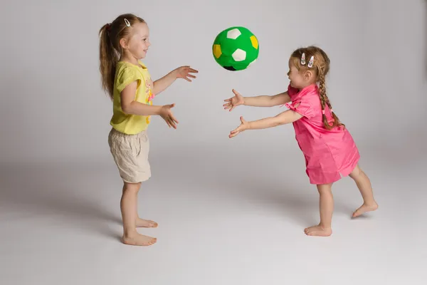 Dos niñas que están jugando con un balón verde, es parte de las actividades para el desarrollo cognitivo