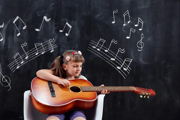 Estimulación musical para el desarrollo cognitivo, una niña tocando la guitarra en un salón